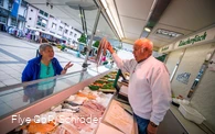 Fischhändler bietet einer Dame Tintenfisch an Fischhändler bietet einer Dame Tintenfisch an