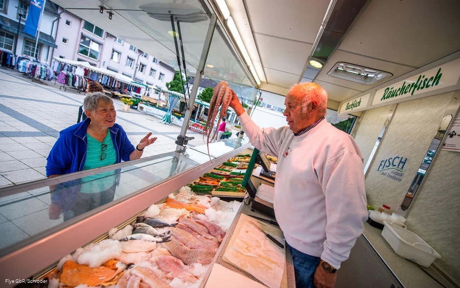 Fischhändler bietet einer Dame Tintenfisch an